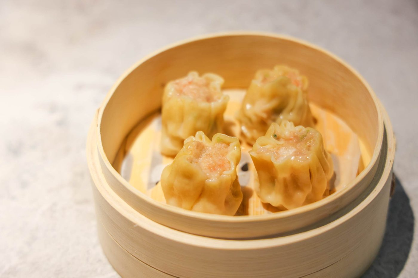Cestello di bambù con siu mai al vapore, ripieni di gambero e maiale.