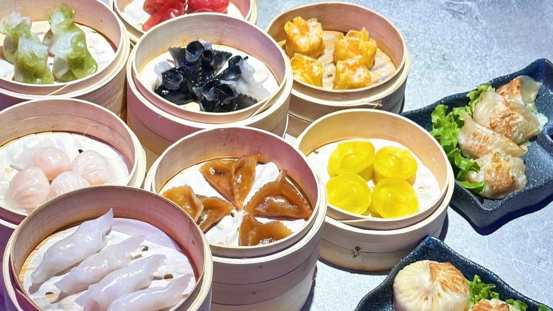 Cestelli di bambù con dim sum colorati: ravioli di gambero, siu mai, ravioli verdi e gialli, appena usciti dal vapore.